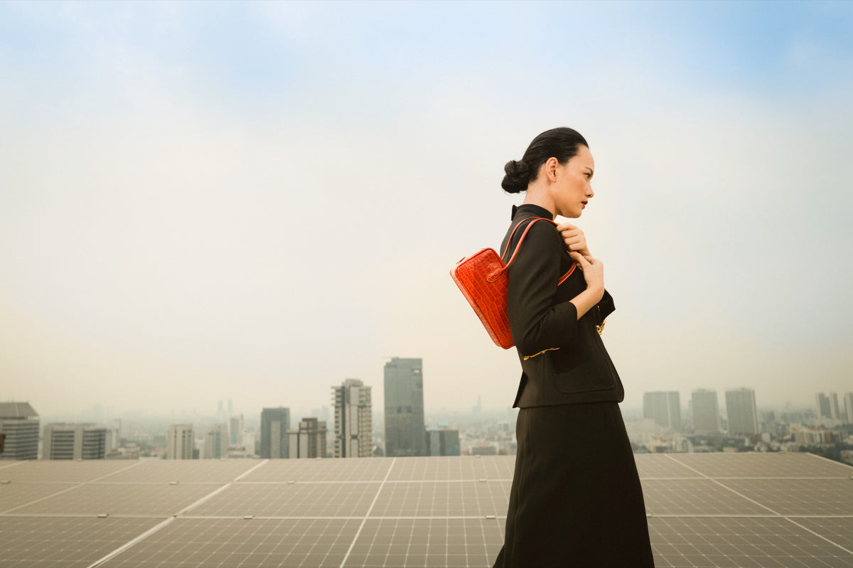 Woman on a city rooftop carrying a red Klove shoulder bag